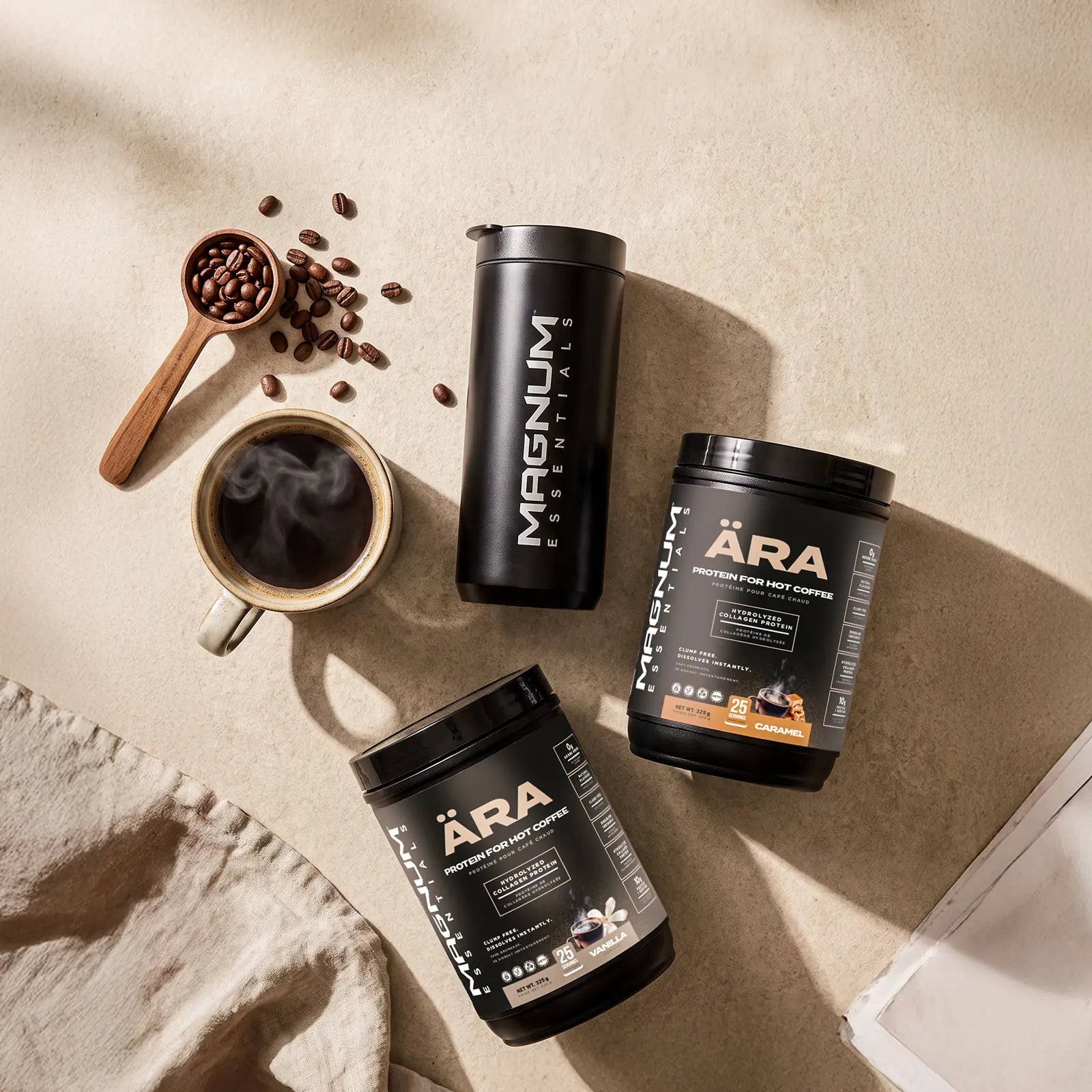 Overhead view of two ÄRA tubs, a matte black Magnum Essentials tumbler, a cup of black coffee and scattered coffee beans on a linen-toned counter